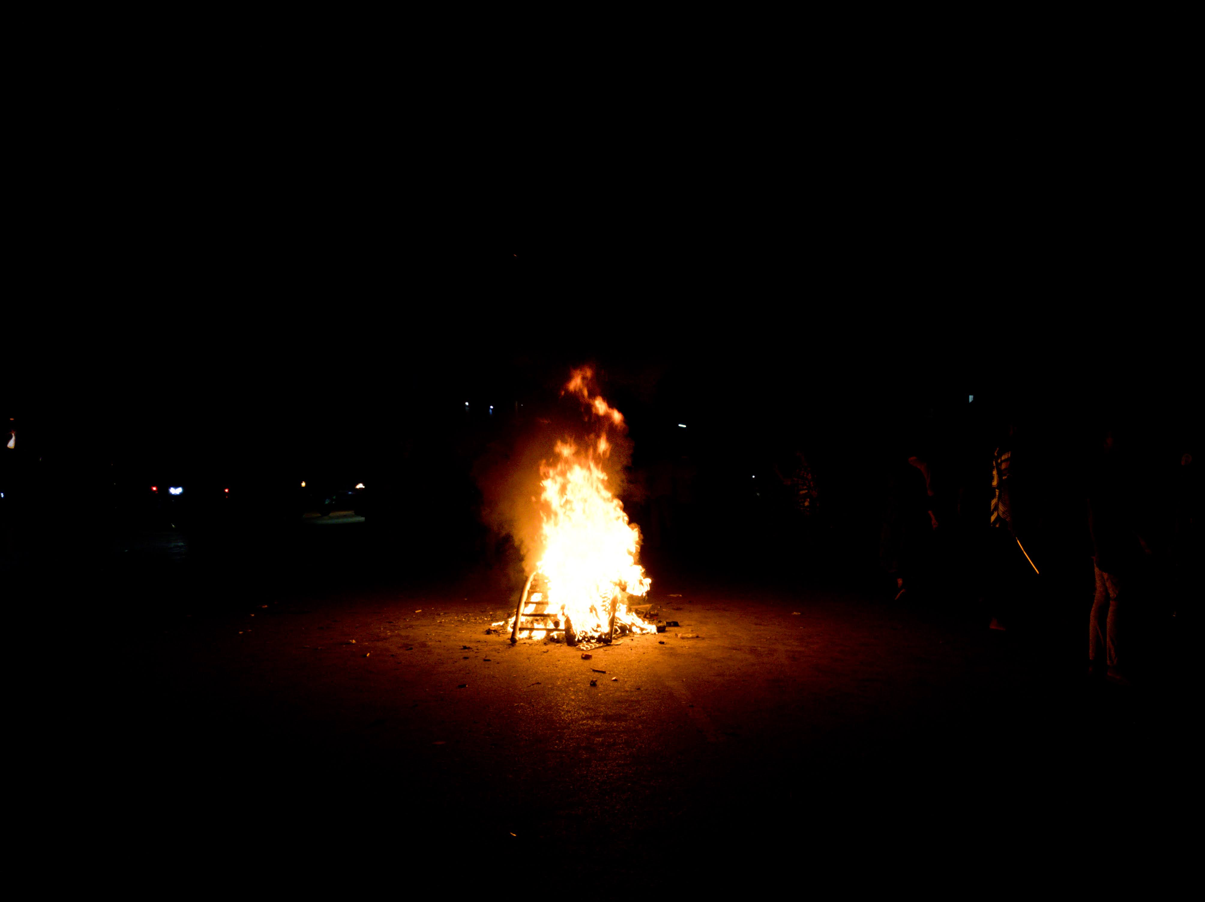 A small bonfire burning brightly in the middle of a dark road by miqdad23.