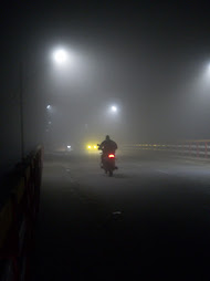Foggy bridge at night with glowing streetlights and a bike by miqdad23.